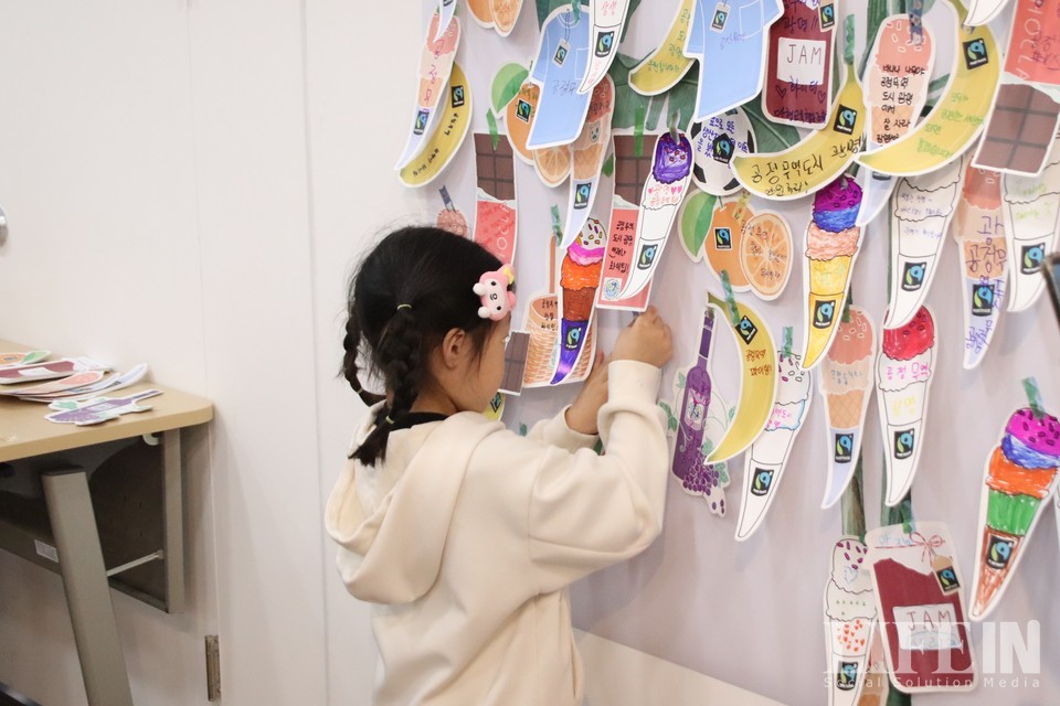 ▲어린이가 공정무역 바나나 나무에 응원 메시지를 달고 있다. ⓒ라이프인