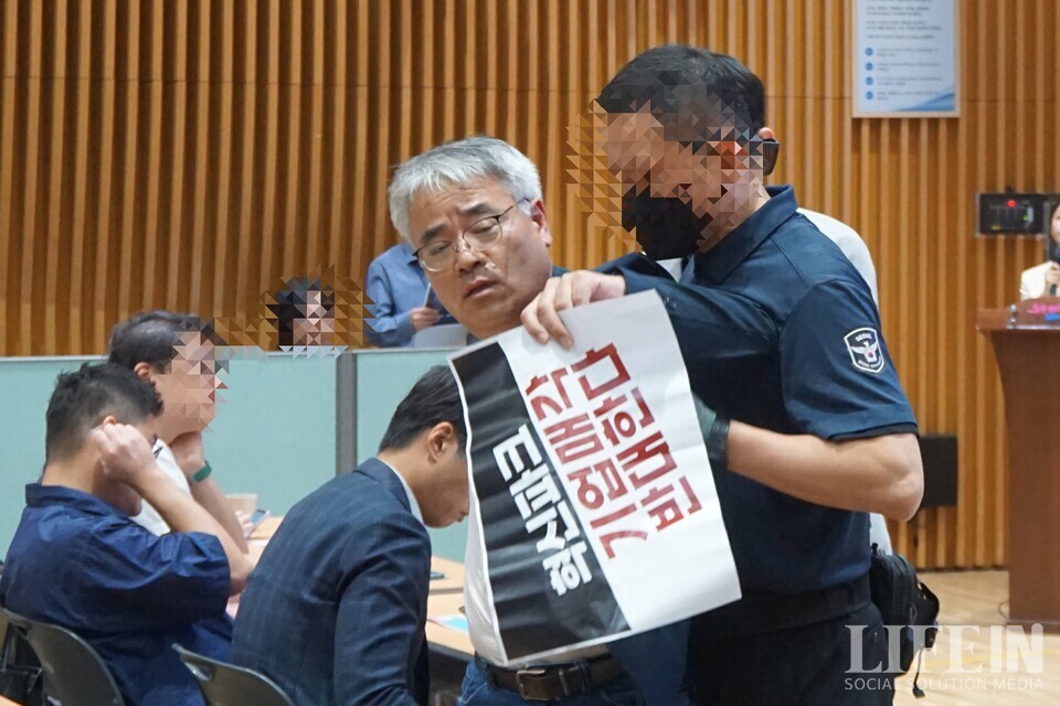 ▲ 서울시 공무원들이 '서울창조타운 조성 기업설명회'에서 '서울혁신파크' 부지 매각을 막으려는 시민활동가(김종민 서울네트워크 공동상황실장)를 제지하고 있다. ⓒ라이프인 