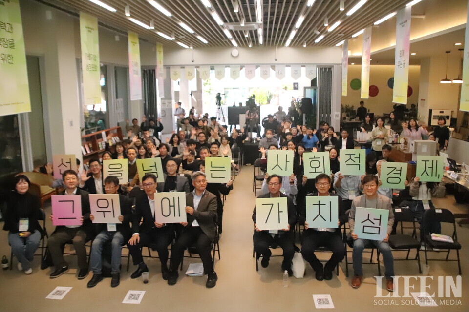 ▲ 25일 제주소통협력센터에서 열린 '사회적경제 활동가 대회' 참석자들이 대회 주제 '선을 넘는 사회적경제, 그 위에 가치 섬'이라고 적힌 팻말을 들고 사진 촬영에 임하고 있다. ⓒ라이프인
