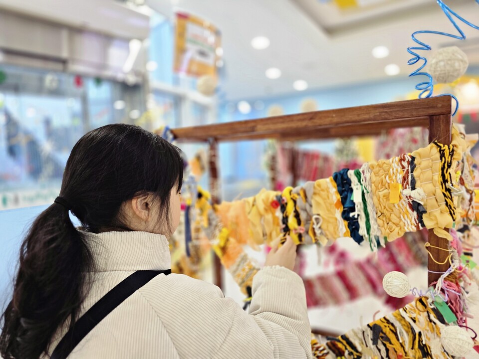 ▲ '실로 재미있는 미술놀이'에 참여한 어린이가 전시회에서 자신이 만든 작품을 들여다보고 있다. ⓒ더스티치