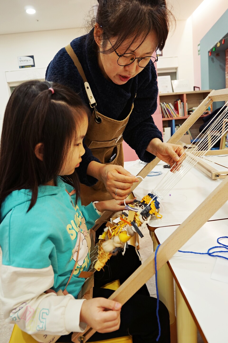 ▲ 최현순 직조 공예작가가 어린이에게 위빙툴 사용방법을 가르쳐 주고 있다. ⓒ더스티치