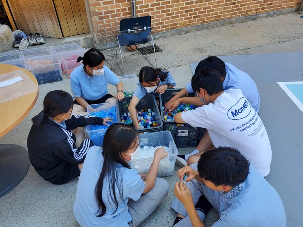 ▲ 나선지대에서 프로그램 참가자들이 플라스틱 병뚜껑을 분류하고 있다. ⓒ희망제작소